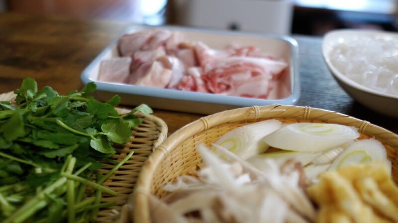 きりたんぽ鍋の材料のせり、鶏もも肉、豚バラ肉、しらたきの写真